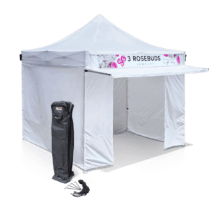 A white pop-up tent with the branding 3 Rosebuds Jewelry on the valance. The tent is set up with walls partially open. A carrying case is placed to the left of the tent.