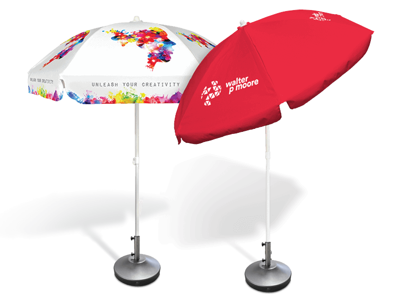 Two beach umbrellas with metal stands. One umbrella is white with colorful splashes and the text Unleash Your Creativity. The other is red with white text and logo walter p moore. Both have adjustable poles and sturdy bases.