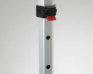 A close-up of a metal pole with evenly spaced circular holes, perfect for securing your 10 x 10 pop up canopy tent. A black clamp featuring a red lever is attached to the pole. The background is plain and light gray.