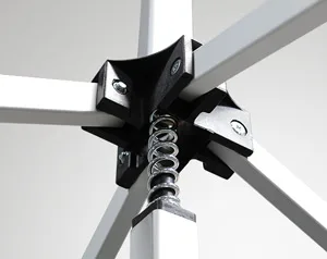 Close-up of a 10 x 10 canopy metal frame structure with a spring mechanism connecting four white bars. The black central connector secures the bars, each held by bolts, under a neutral grey background.