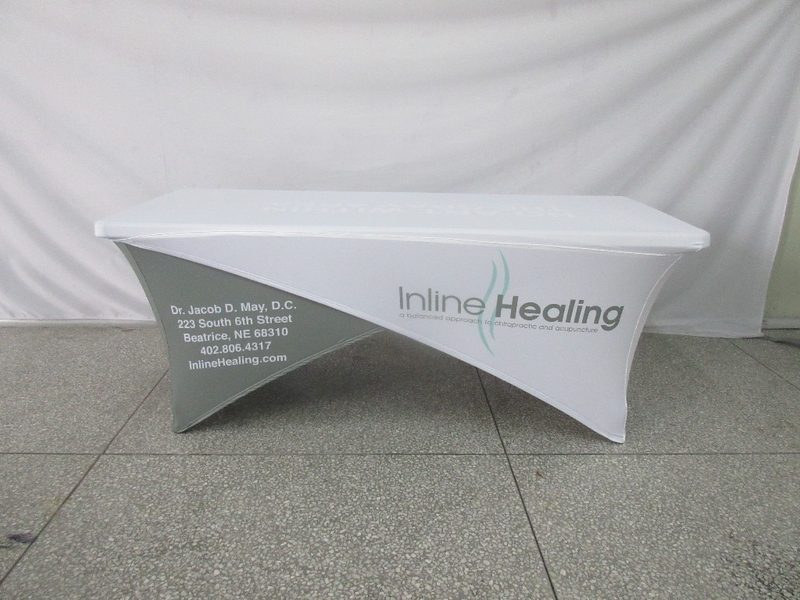 A Cross-Stretch Table Cover - Fully Printed in white and gray showcases contact information for Dr. Jacob D. May, a chiropractor, featuring the facility's name, Inline Healing, along with its address in Beatrice, NE, and includes a phone number and website details.
