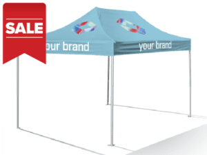 A vibrant pop-up tent featuring colorful geometric designs and the text "SALE: 10’x15′ Printed Pop Up Tent" in blue, is set on a metal frame and displayed on concrete. A red sale banner is prominent in the top left corner. Price: $999.
