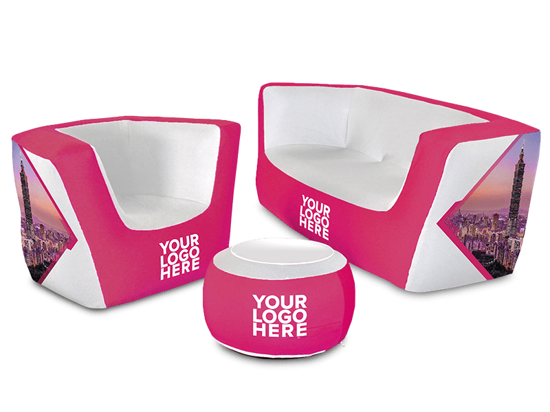 The Custom Air'Lounge Inflatable Furniture Set includes a chair, a sofa, and a round ottoman in pink and white, featuring the "Your Logo Here" text and decorated with city skyline graphics on the sides.