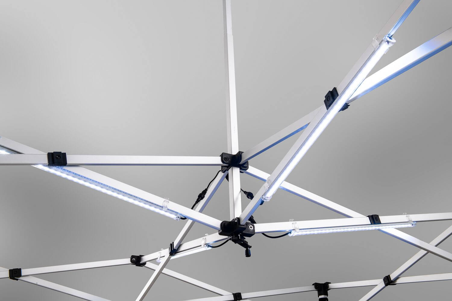 A close-up view of the LED Light Kit for Pop-Up Canopy, featuring a geometric framework of intersecting white beams with several LED light strips attached, set against a plain gray background.